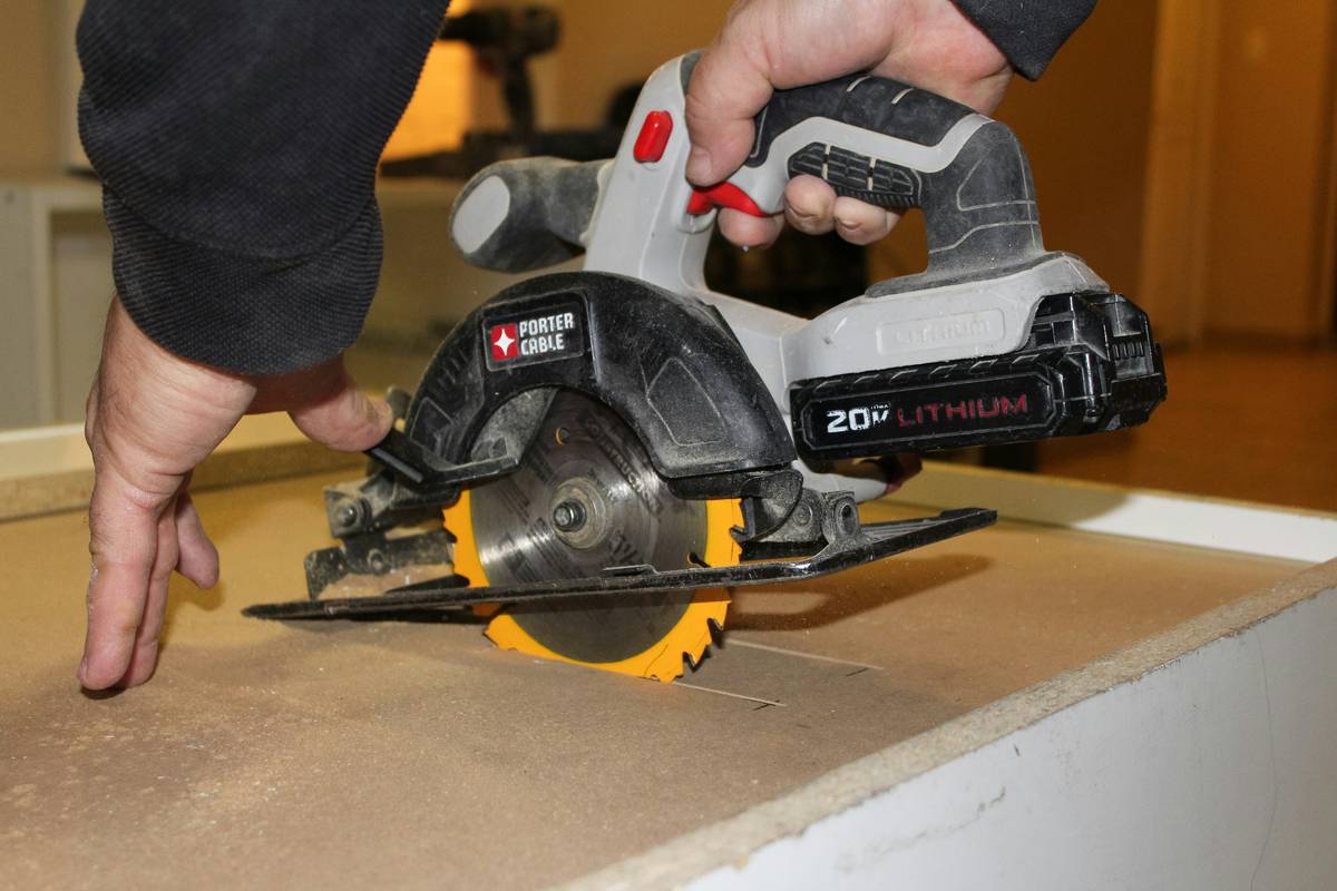 Total tools scroll saw cutting intricate wooden design on workbench