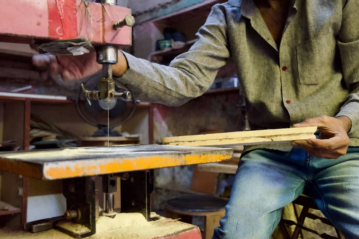 Close-up of hands using a scroll saw for woodworking on cherry wood, showing fine curve detail